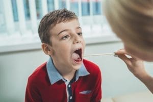Nurse checks child for strep throat